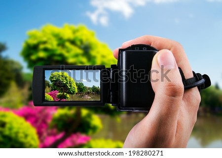 Video camera or camcorder recording flora in japanese garden 