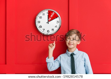 Little boy near clock with timer for 10 minutes on color background. Time management concept Royalty-Free Stock Photo #1982814578