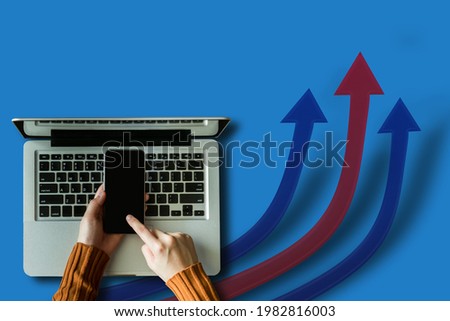 Top view of businesswoman hands using smartphone with laptop computer and three flat arrows rising up on blue background. 