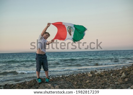Young boy holding flag of Mexico at the Sea"September 16. Independence Day of Mexico".