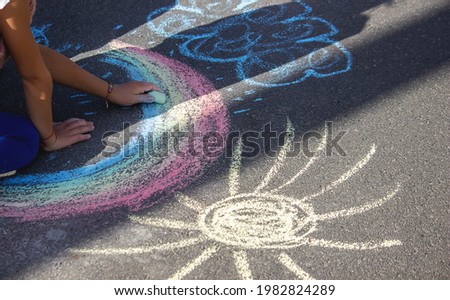 Cute little child draws the sun with chalk outdoors, summer time, chalk. Selective focus. Nature