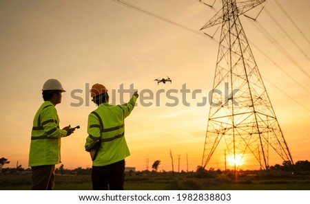 Two electrical engineers used drones to observe the planning work, producing electric power at high voltage electrodes Royalty-Free Stock Photo #1982838803