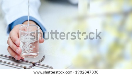 Composition of hand holding liquid in chemistry beaker, with blurred copy space to right. medical and science research concept digitally generated image.