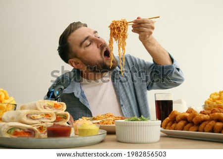 Food blogger eating in front of microphone at table against light background. Mukbang vlog Royalty-Free Stock Photo #1982856503