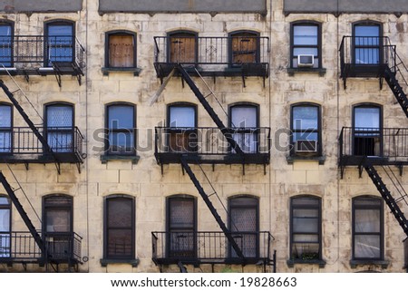 Three floors of windows with fire escapes on the facade of a New York apartment building that is in desperate need of paint and repairs. Royalty-Free Stock Photo #19828663