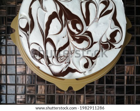 Yogurt cake with chocolate dressing on mosaic table. Delicious sweet dessert rich of carbohydrates. Flat lay food photo with floral pattern and detailed texture. Art of confectionery in pastry shop. 