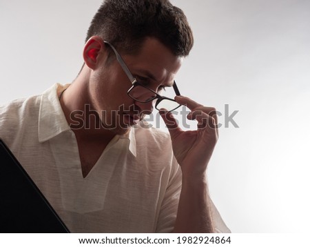 Man teacher adjusts his glasses. Portrait of a guy working as a lector. Guy on a white background. Man teacher is thinking about something. Pensive Man teacher. He teaches at school or college Royalty-Free Stock Photo #1982924864