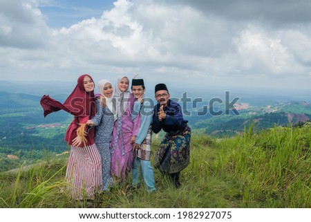 Funny muslim family greeting gesture during eid al fitr. Family posing in free expression to greeting eid al fitr on the top of the hill.