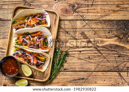 Tacos with beef meat, onion, tomato, sweet pepper and salsa. Mexican food. wooden background. Top view. Copy space