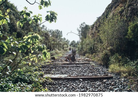 traveler with a backpack in the middle of the abandoned train tracks