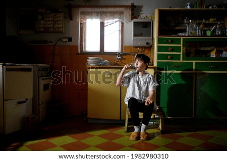 Small girl brushing teeth in kitchen indoors at home, poverty concept. Royalty-Free Stock Photo #1982980310
