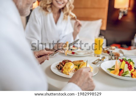 Breakfast time. A couple in white robes having breakfast and looking pleased
