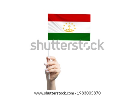Beautiful female hand holding Tajikistan flag, isolated on white background.