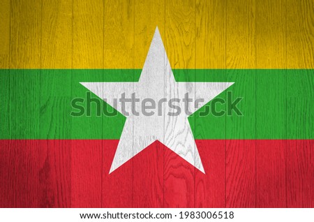 The flag of Myanmar on a grunge wooden background.