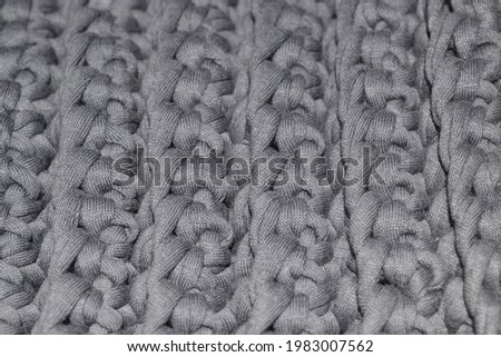 Background close-up of gray canvas,crocheted,yarn-knitwear.Dense,three-dimensional pattern.Handmade concept,hobby, online course on knitting fashion items,knitted interior items,bags,carpets.Copyspace