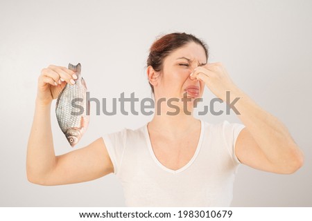 Caucasian woman opposes the disgusting smell of fish. A metaphor for women's health and intimate hygiene. Royalty-Free Stock Photo #1983010679