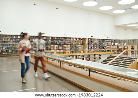 Blurred motion of people walking along the corridor in big library