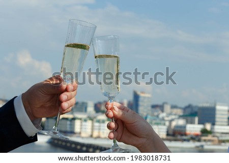 two glasses of champagne in the hands of the newlyweds against the backdrop of the city landscape