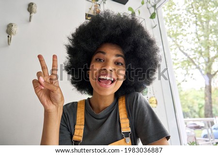 Young happy African American generation z student female hipster recording vlog indoor. Webcam view of smiling teenage beauty blogger influencer speaking to friend online in virtual video call. Royalty-Free Stock Photo #1983036887