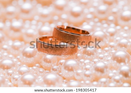  Couple of gold wedding rings on scatterings of pearls. Wedding accessories.