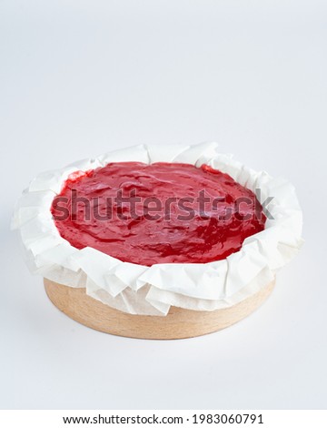 Mini cheesecake with red fruits jam topping on recycle Mini Wooden Baking Mold, white background, space for text, selective focus.