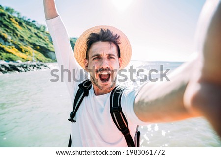 Happy young tourist taking selfie at beach on vacation - Millennial guy having fun smiling at camera - People and holidays concept