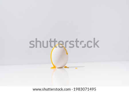 Egg yolk falling on an egg in a white table with gray background. Isolated