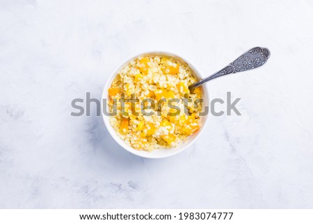 Millet porridge with pumpkin slices in light forms for baking on a light background. Vegetarian diet. Traditional autumn cuisine. top view.