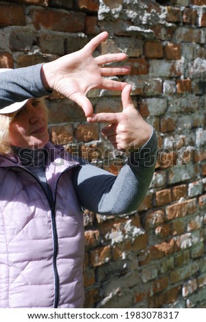 A girl near a brick wall with her hands imagines a camera. St. Veronica's Day Photographer's Day .
