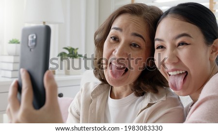 Attractive beautiful two people asia young lady girl use mobile phone take photo picture video camera overjoy sit at home sofa couch have good time day together quarantine in mum healthy health care.