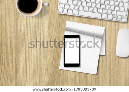 A computer desk with keyboard, smartphone, stationery and coffee cup.