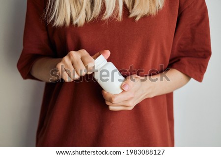 Woman pours pills or vitamins from a jar onto her hand. Taking vitamins or medications. The concept of health care, medicine, pharmacies, disease prevention. A jar with pills or vitamins in the hands 