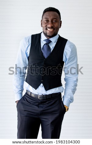 Portrait executive smart handsome successful African businessman or male leader wearing formal clothes with necktie, smiling, standing and putting hands in pants pocket with profession and confidence
