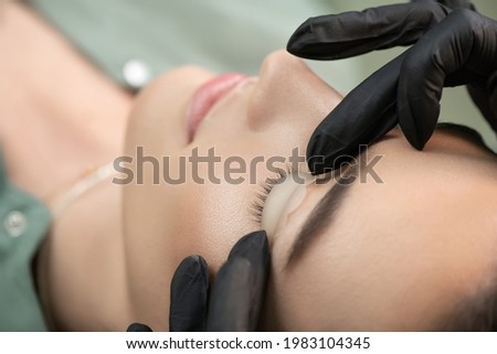 Master fits white curl for lashes. Eyelash Care Treatment: lifting and curling, lash lamination and extension for lashes.  Close-up of beauty model's face during lash lift laminating botox procedure. Royalty-Free Stock Photo #1983104345