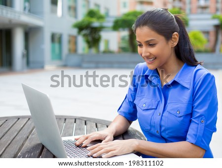 Closeup portrait, young pretty woman in blue shirt resting hands on keyboard, browsing digital computer laptop, isolated background of sunny outdoor, green trees, office background Royalty-Free Stock Photo #198311102