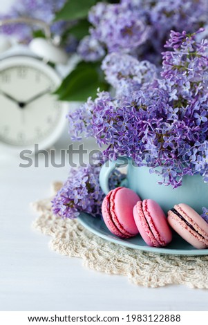 Postcard with violet lilac bouquet in a blue cup and delicious french macarons. Template for birthday card, greeting for Mother's Day, Saint Valentine's day, 8 March, Women's Day. White background