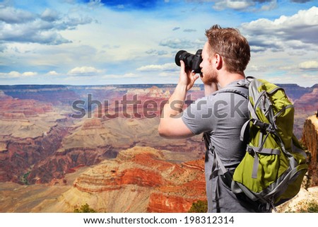 Young man with backpack taking a photo on the top of mountains at Grand Canyon, caucasian