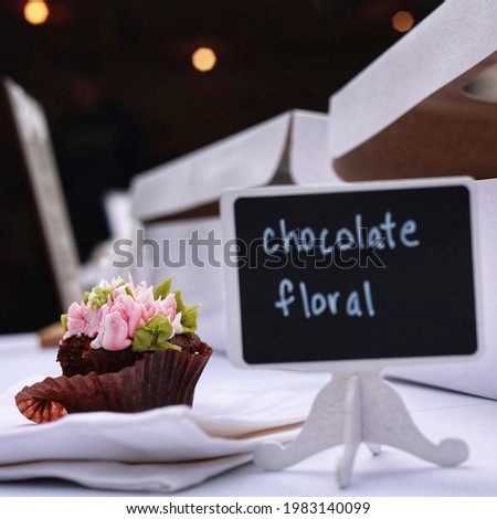 Chocolate cupcake with floral frosting and chalkboard sign label