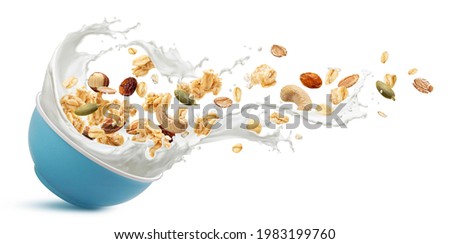 Falling crunchy muesli, bowl of oat granola with milk splashing isolated on white background Royalty-Free Stock Photo #1983199760