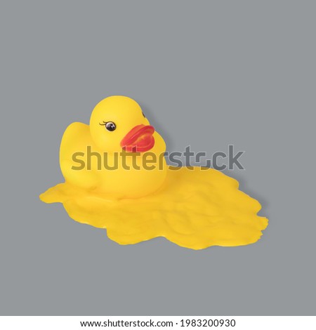 Creative minimal idea with a yellow duck dipped in paint on an ultimate gray background. Copy space