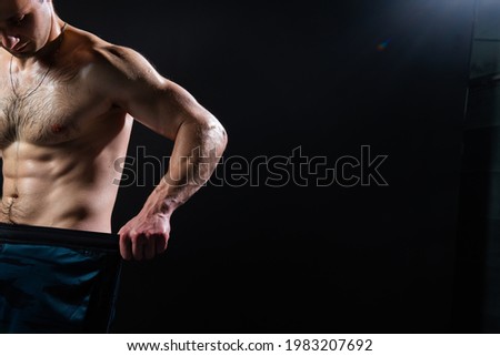 Man on black background keeps dumbbells pumped up in fitness biceps black, arm muscular man bodybuilder powerful, pectoral. Lift sportive adult, guy fit Look at the press and measures the size of Royalty-Free Stock Photo #1983207692