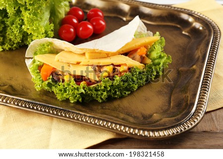Veggie wrap filled with chicken and fresh vegetables on tray, close up