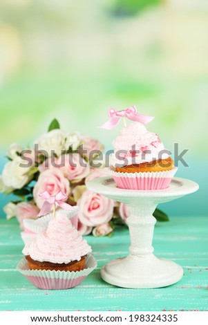 Tasty cup cakes with cream on blue wooden table