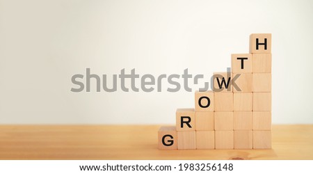 Wooden cubes block on white background printed screen growth wording.  Target of investment, business growth concept, project achievement, market trend, economy trend and performance concept
