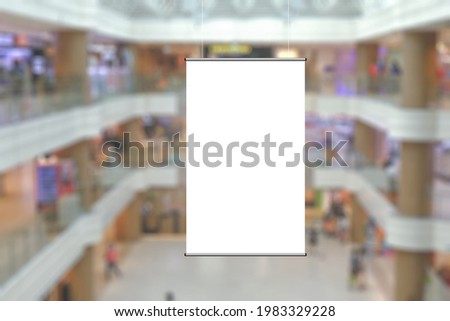Blank advertising poster banner mockup in modern retail environment; vertical hanging billboard in shopping mall, out-of-home OOH media display space; blur background