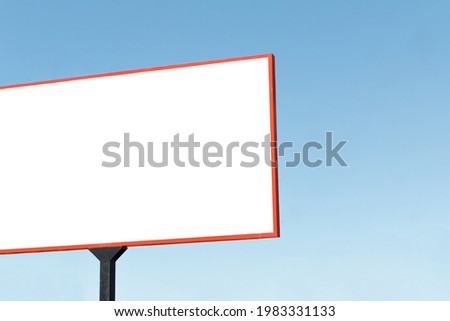 Big white Billboard with Red Frame on Blue Sky Background during Daytime. Blank mock up of the Billboard on a street
