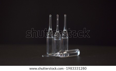 Glass transparent ampoules. Transparent liquid. Medicine. Vaccine against the virus. Medical drug. Solution for injections. Black background. Close-up.