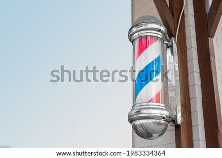 American vintage barber pole sign with a helical stripe (red, white, and blue) on the wall of a Barber's shop