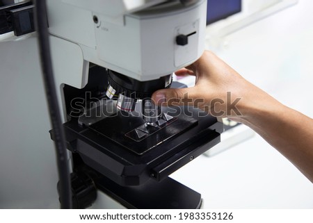 Workers adjust the magnification of microscope to see microstructure of metal. Royalty-Free Stock Photo #1983353126