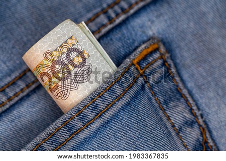 Lots of Polish 200pln banknotes sticking out of the back pocket of denim pants. Photo taken under artificial, soft light